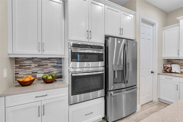 kitchen with light stone counters, appliances with stainless steel finishes, white cabinetry, and decorative backsplash