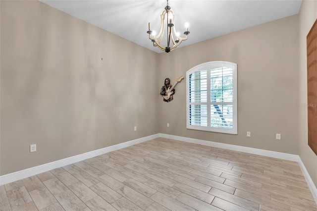 unfurnished room featuring an inviting chandelier, light wood-style flooring, and baseboards