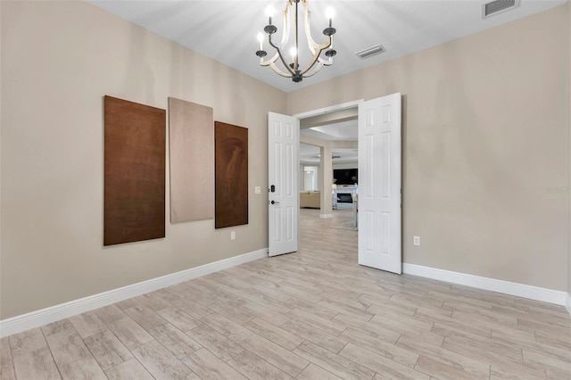 spare room featuring light wood-style floors, visible vents, and baseboards