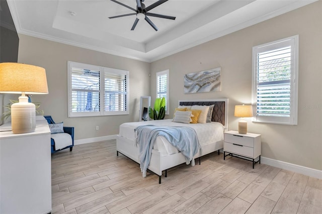 bedroom with crown molding, a raised ceiling, ceiling fan, light wood-type flooring, and baseboards