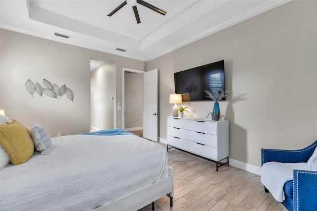 bedroom with baseboards, a raised ceiling, visible vents, and light wood-style floors