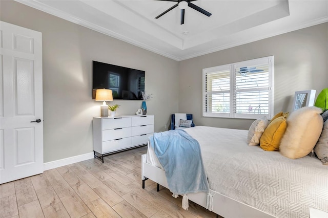 bedroom featuring light wood-style flooring, a ceiling fan, baseboards, a raised ceiling, and crown molding