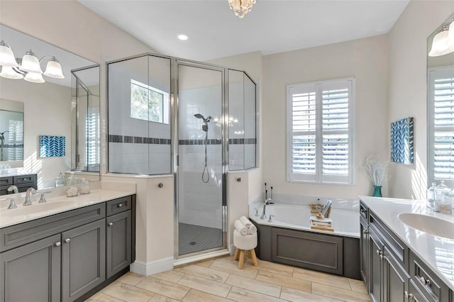 full bath featuring a stall shower, two vanities, and a sink