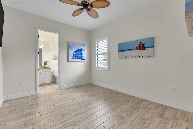 unfurnished bedroom with light wood-style floors, ensuite bath, and baseboards