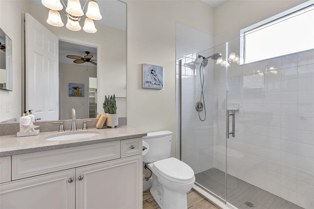 full bathroom with vanity, a shower stall, toilet, and ceiling fan with notable chandelier