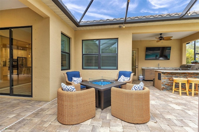 view of patio / terrace with a lanai, an outdoor fire pit, and an outdoor kitchen