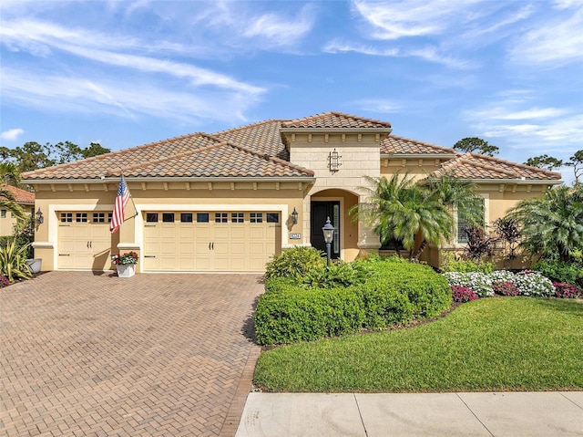 mediterranean / spanish home with an attached garage, a front yard, decorative driveway, and stucco siding