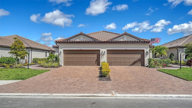 view of front of home with an attached garage, a tiled roof, decorative driveway, and stucco siding