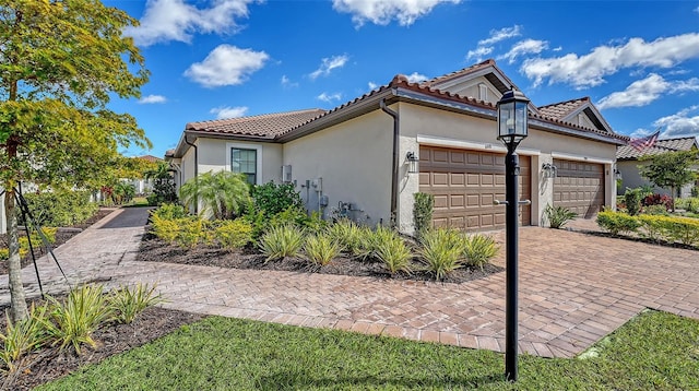 view of home's exterior featuring a garage, a tiled roof, decorative driveway, and stucco siding