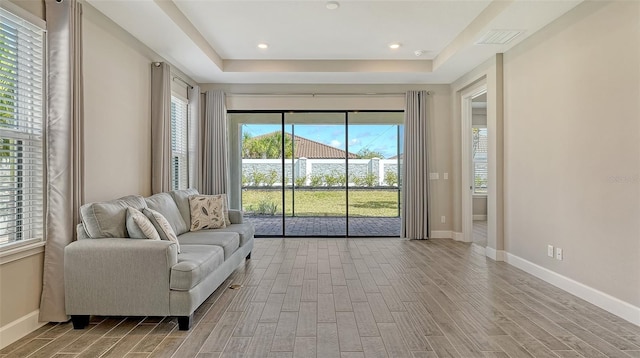 sitting room featuring a raised ceiling, baseboards, and wood finished floors