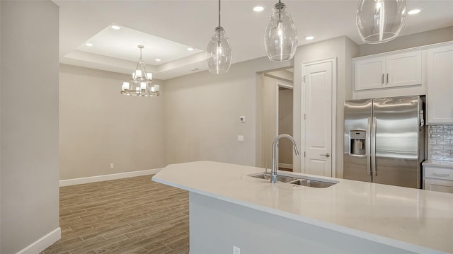 kitchen featuring recessed lighting, stainless steel fridge with ice dispenser, a sink, wood finished floors, and baseboards