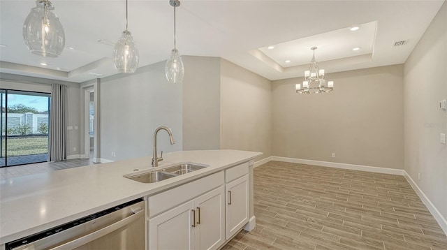 kitchen with wood finish floors, a sink, light countertops, dishwasher, and a raised ceiling