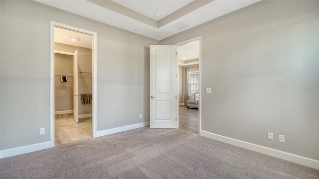 unfurnished bedroom with carpet floors, visible vents, a spacious closet, and baseboards