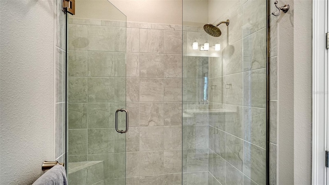 full bath with a textured wall and a shower stall