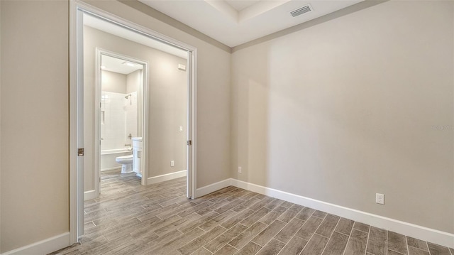 unfurnished room featuring baseboards, visible vents, and wood finished floors