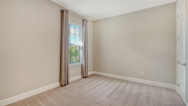 empty room featuring light carpet and baseboards