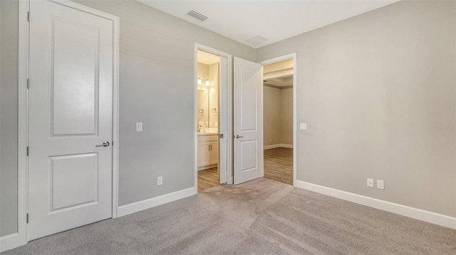 unfurnished bedroom with carpet floors, connected bathroom, visible vents, and baseboards