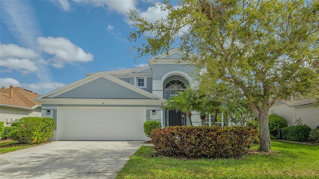 view of front of property featuring driveway, a front lawn, an attached garage, and stucco siding