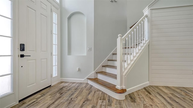 foyer entrance featuring stairs, wood finished floors, and baseboards