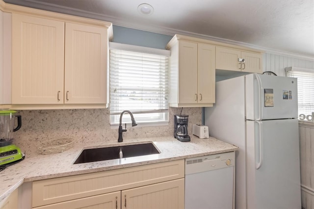 kitchen with ornamental molding, white appliances, a sink, and light stone countertops