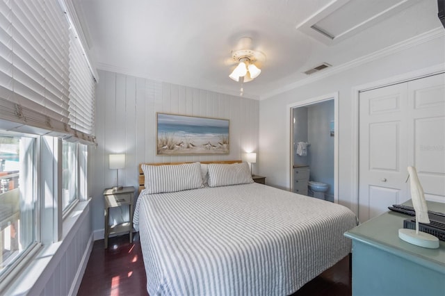 bedroom with attic access, visible vents, connected bathroom, dark wood-style floors, and crown molding