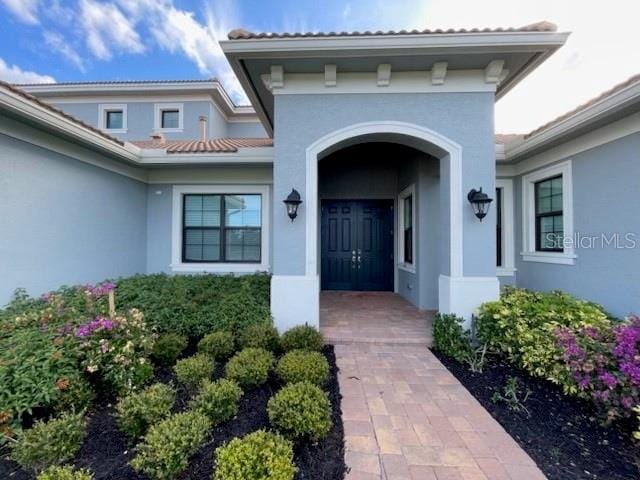 doorway to property with a tiled roof and stucco siding