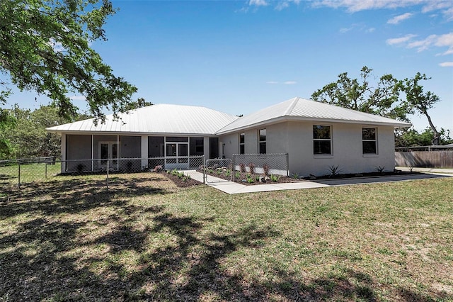 back of house with fence, a yard, a sunroom, stucco siding, and metal roof