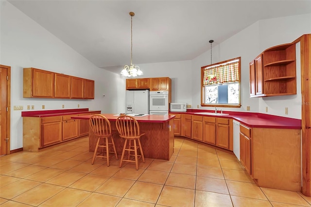 kitchen with light tile patterned floors, white appliances, a kitchen island, and a sink