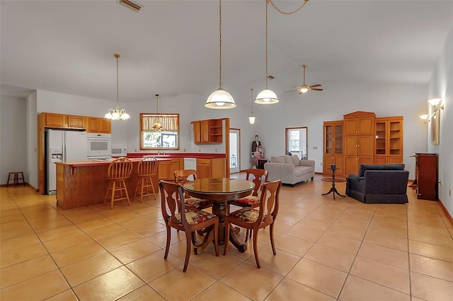 dining area with light tile patterned flooring, a ceiling fan, visible vents, and high vaulted ceiling