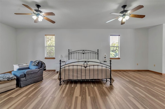 bedroom with baseboards, multiple windows, and wood finished floors