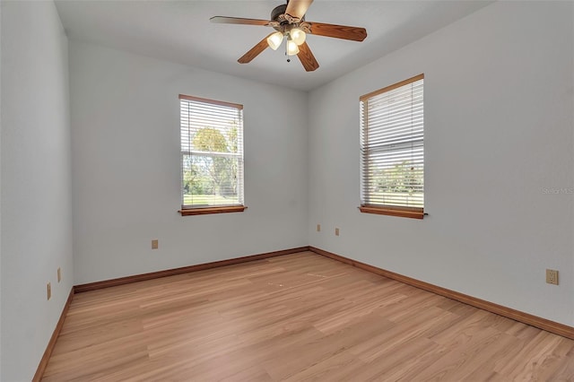 spare room with a ceiling fan, light wood-style floors, and baseboards