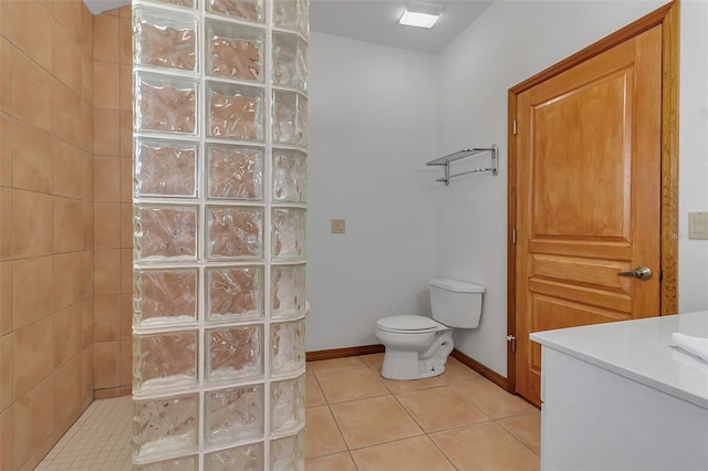 bathroom with tile patterned flooring, toilet, a walk in shower, and baseboards