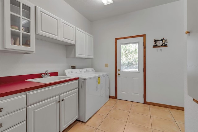 laundry room with baseboards, light tile patterned flooring, cabinet space, a sink, and washer and dryer