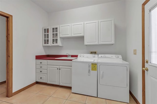 washroom featuring light tile patterned floors, baseboards, cabinet space, a sink, and washer and dryer