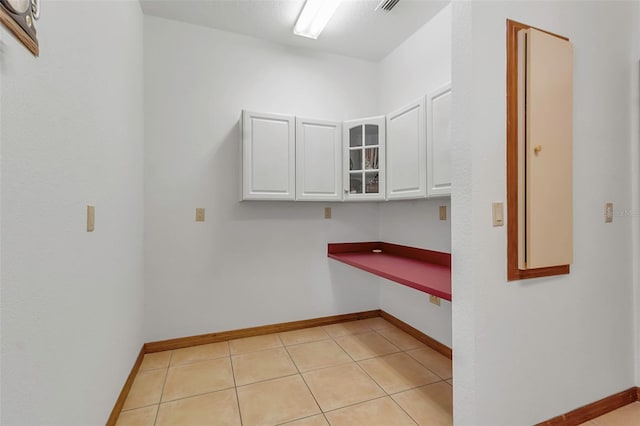 clothes washing area with light tile patterned floors and baseboards