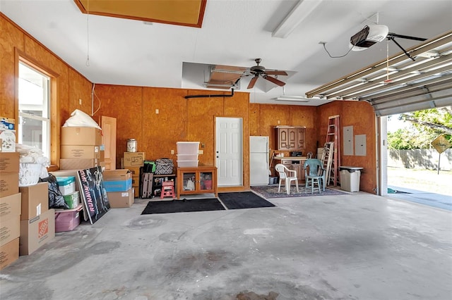 garage with electric panel, wood walls, a garage door opener, and freestanding refrigerator