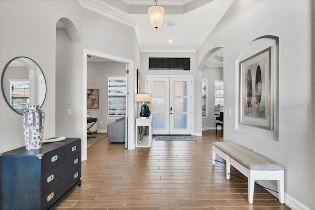 entrance foyer with ornamental molding, wood tiled floor, and arched walkways