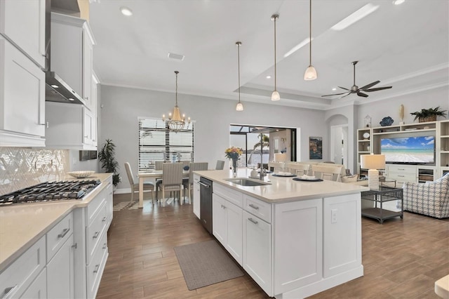 kitchen featuring arched walkways, white cabinets, a raised ceiling, stainless steel appliances, and a sink