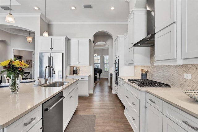 kitchen featuring wall chimney exhaust hood, visible vents, stainless steel appliances, and arched walkways