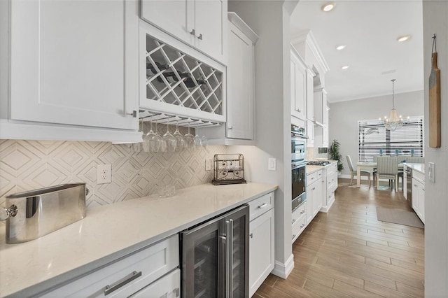 kitchen with a notable chandelier, beverage cooler, white cabinetry, ornamental molding, and tasteful backsplash