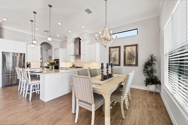 dining space featuring light wood-style flooring, visible vents, arched walkways, and ornamental molding