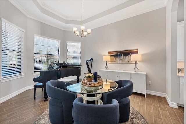 dining space featuring a chandelier, baseboards, a raised ceiling, and wood tiled floor