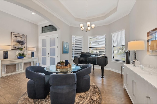 dining area featuring arched walkways, a tray ceiling, wood finished floors, and a notable chandelier