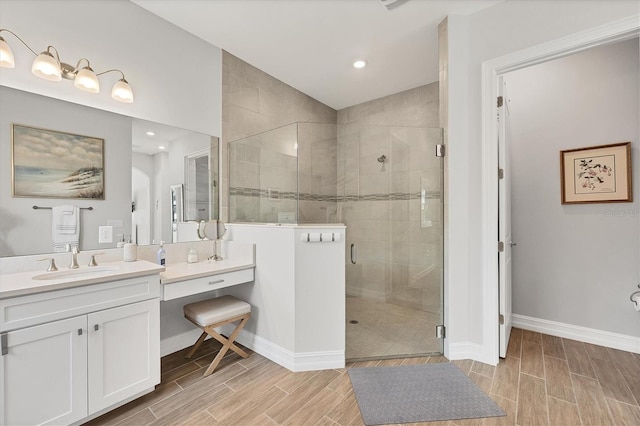 bathroom with a stall shower, baseboards, vanity, wood finish floors, and recessed lighting