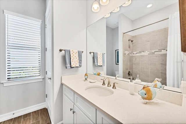 full bath with toilet, vanity, baseboards, tiled shower, and wood tiled floor