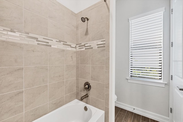 bathroom featuring wood tiled floor, baseboards, tub / shower combination, and toilet