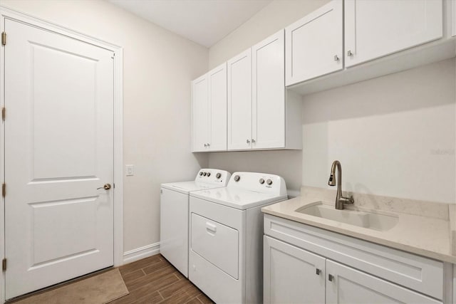 laundry room featuring cabinet space, wood tiled floor, a sink, separate washer and dryer, and baseboards