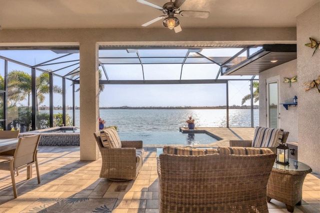 view of patio featuring ceiling fan, a lanai, an in ground hot tub, a water view, and an outdoor living space