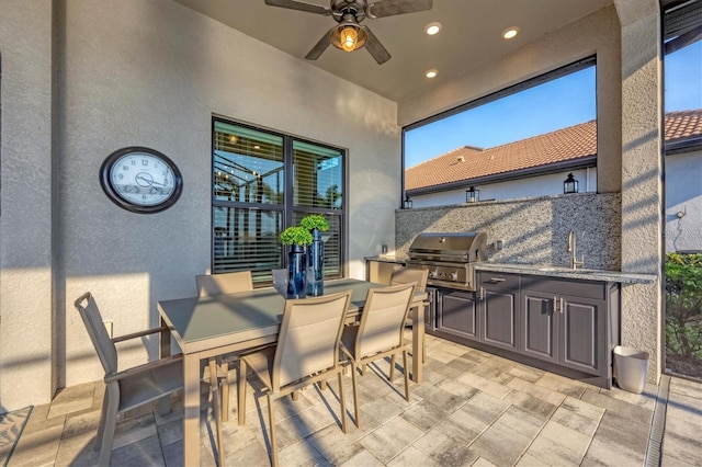 view of patio with an outdoor kitchen, a ceiling fan, grilling area, outdoor dining area, and a sink