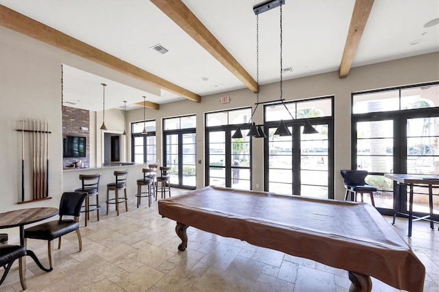 recreation room featuring stone tile flooring, visible vents, beamed ceiling, and a healthy amount of sunlight